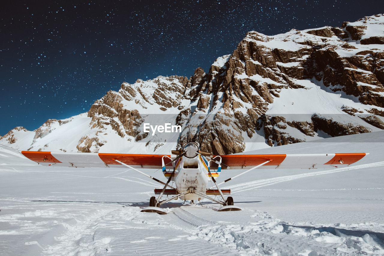 Propeller airplane on snow covered field at dusk