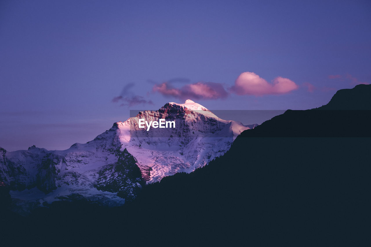 Scenic view of snowcapped mountains against sky at sunset