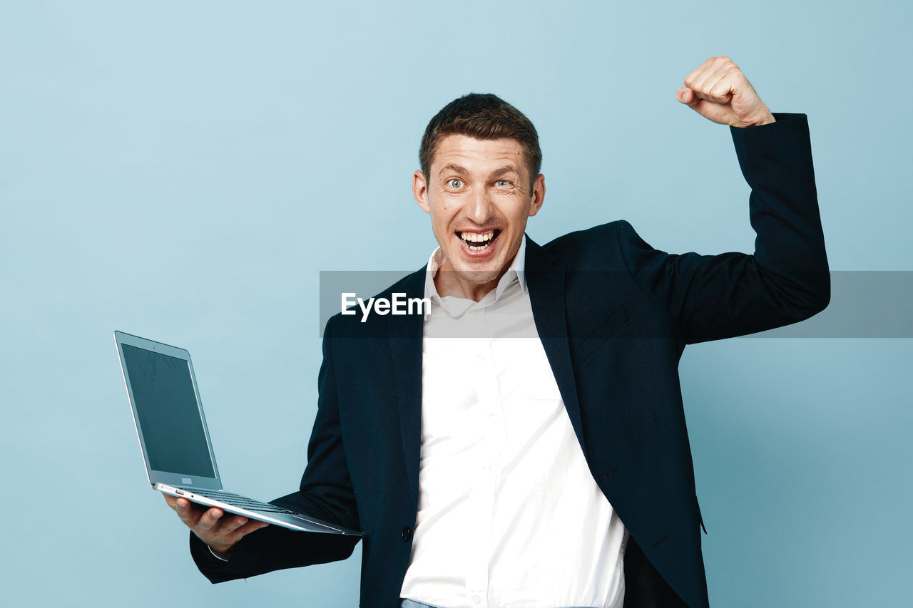 portrait of young man using laptop while standing against white background
