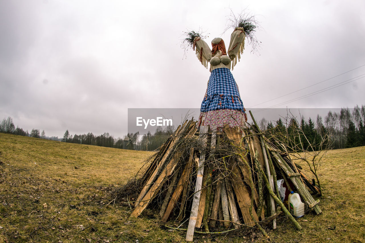 Low angle view of scarecrow on wooden planks against sky