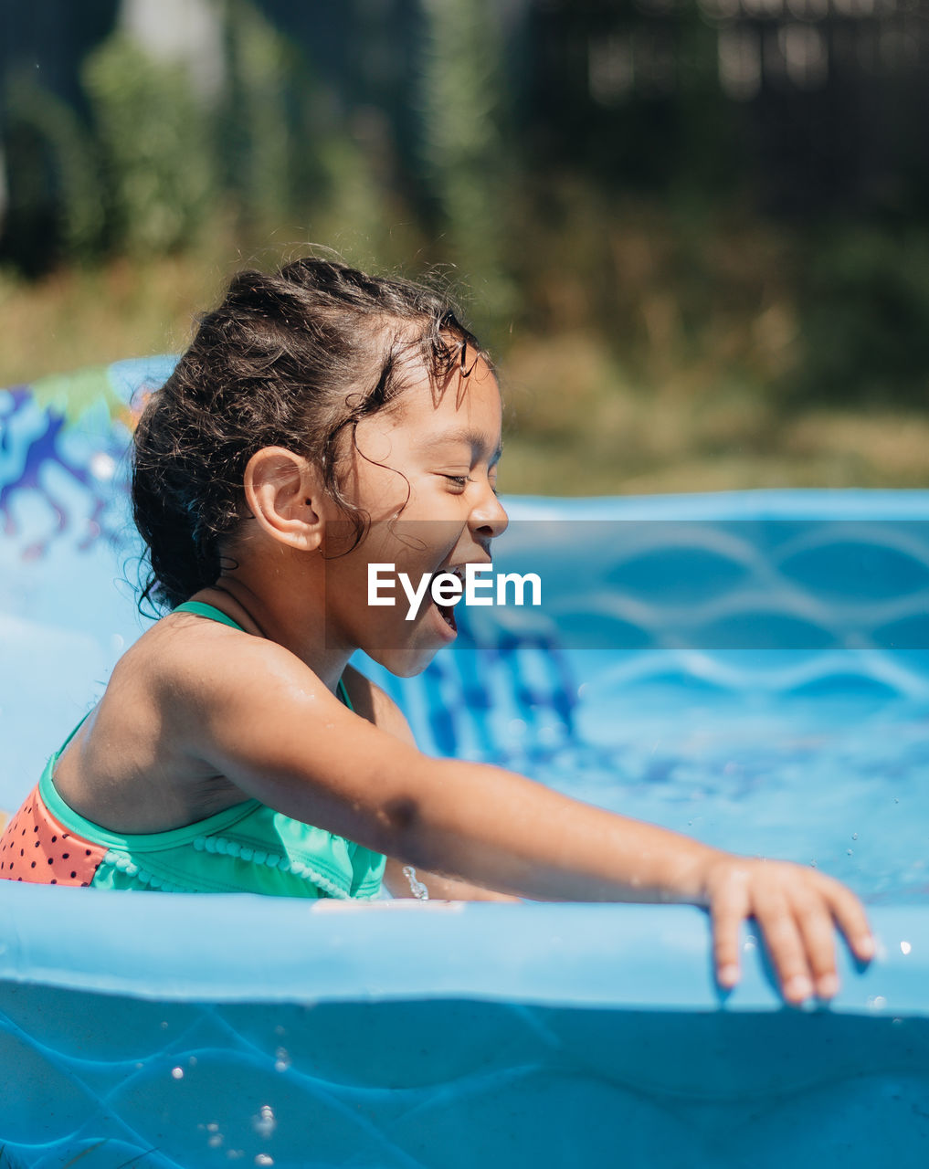 Mixed race young girl at home having fun on hot summer day in kiddie pool