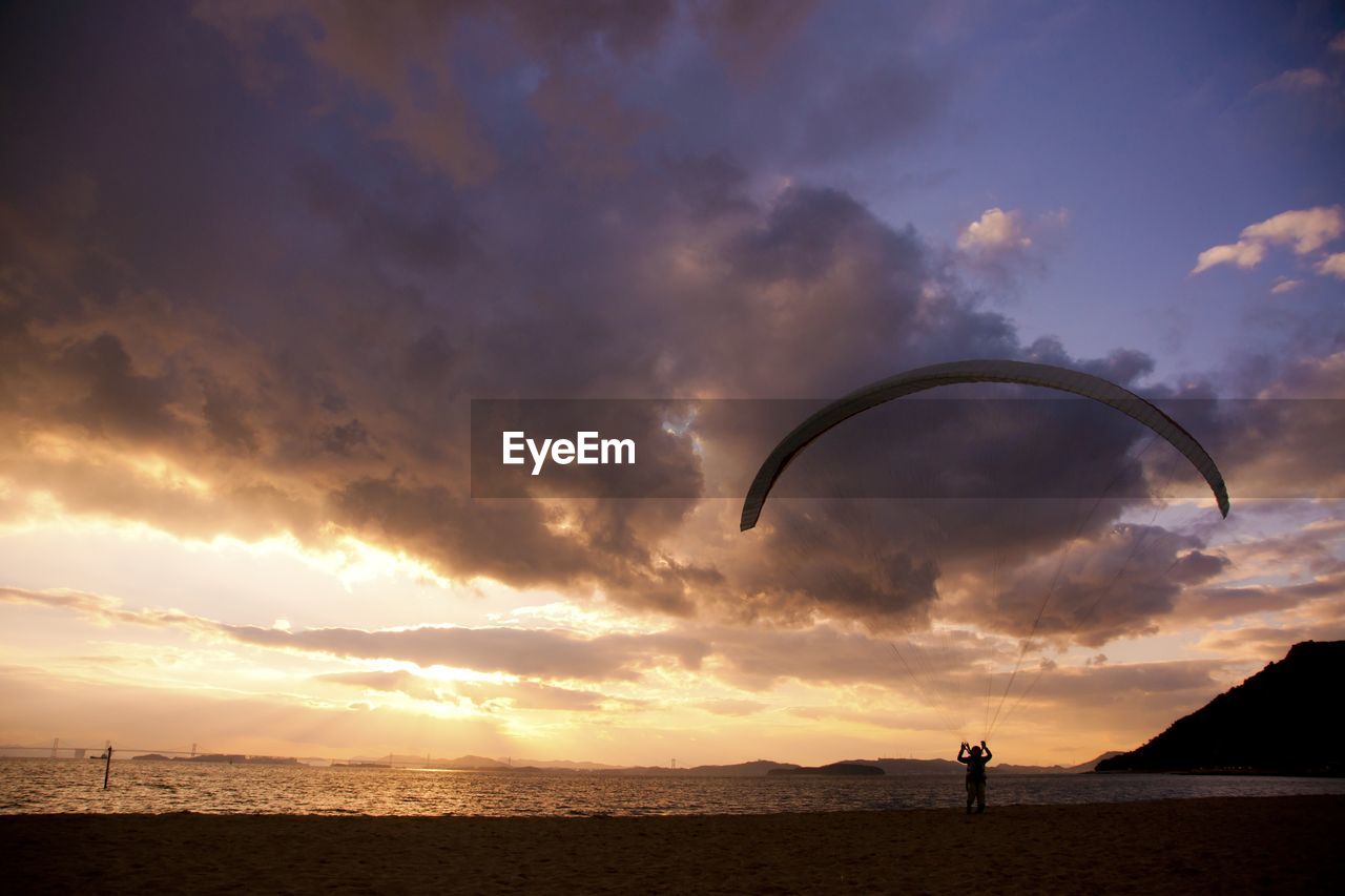 SILHOUETTE PERSON AGAINST SEA DURING SUNSET