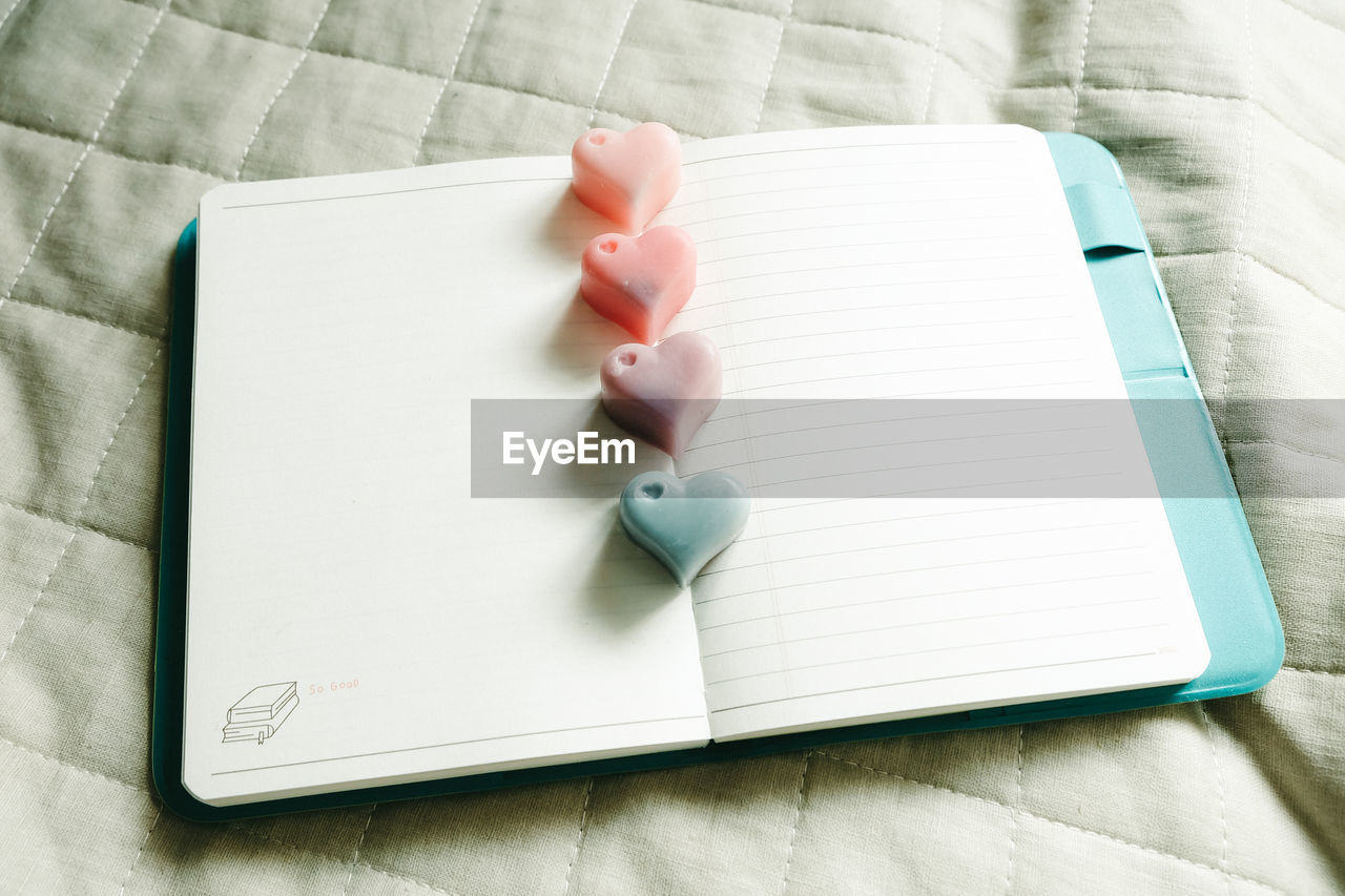 High angle view of heart shape candies on book over table