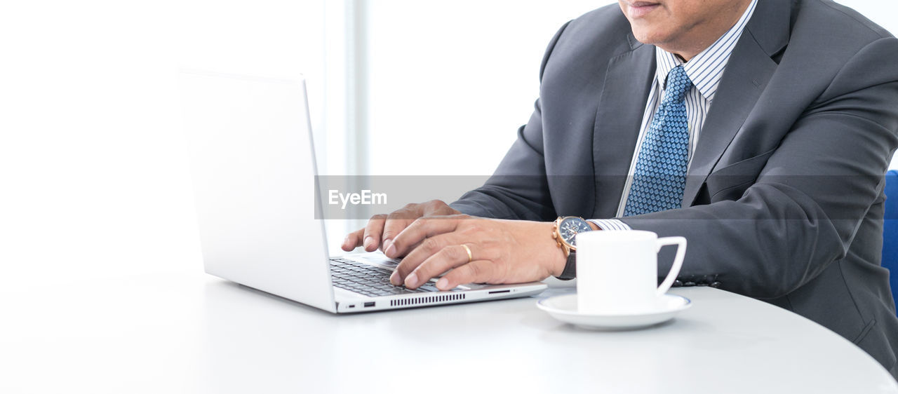 MIDSECTION OF MAN USING LAPTOP