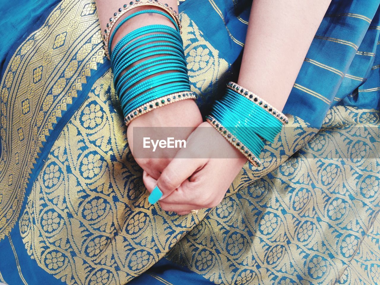 Midsection of woman in blue sari and bangles