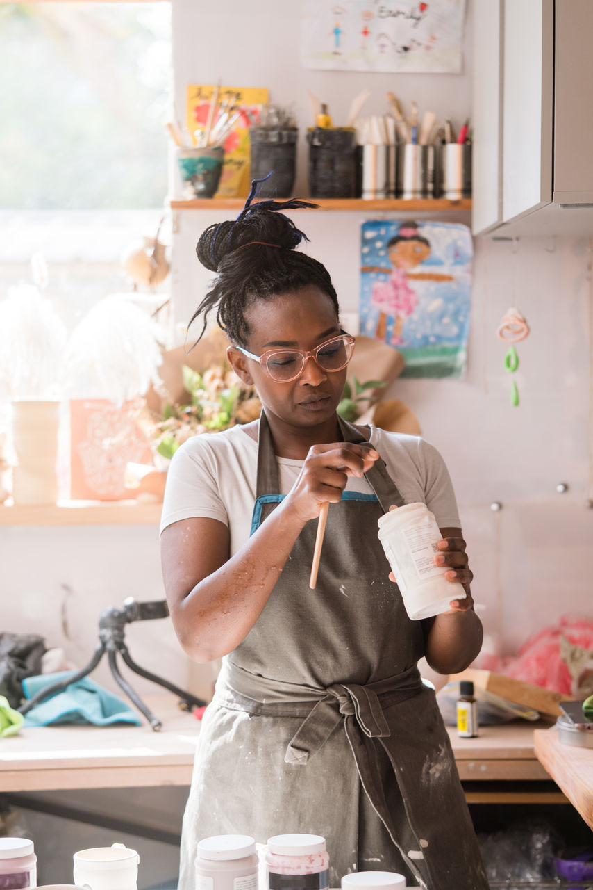 Woman taking paint out of the jar at ceramic studio