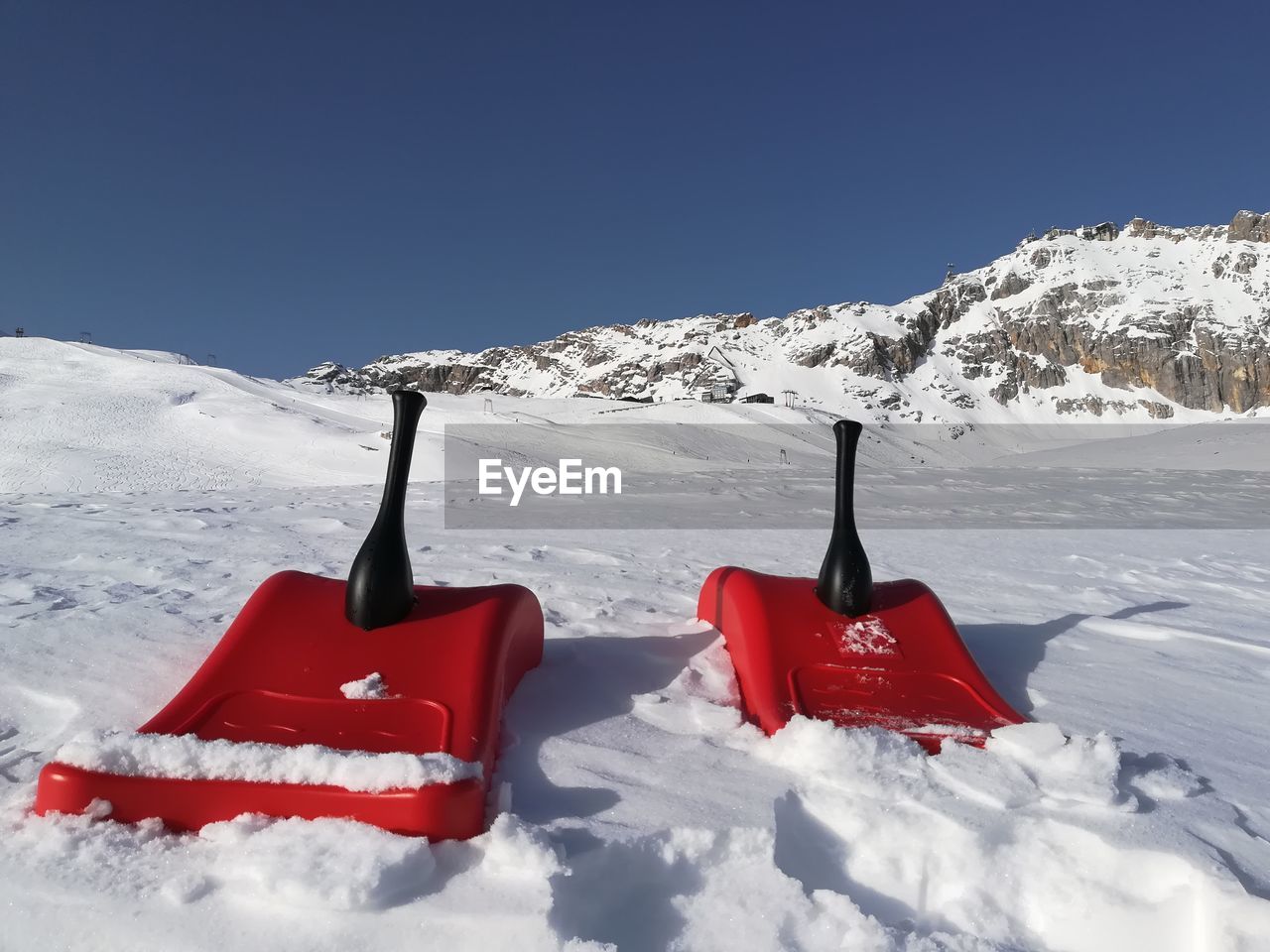 RED FLAG ON SNOW COVERED MOUNTAINS AGAINST SKY