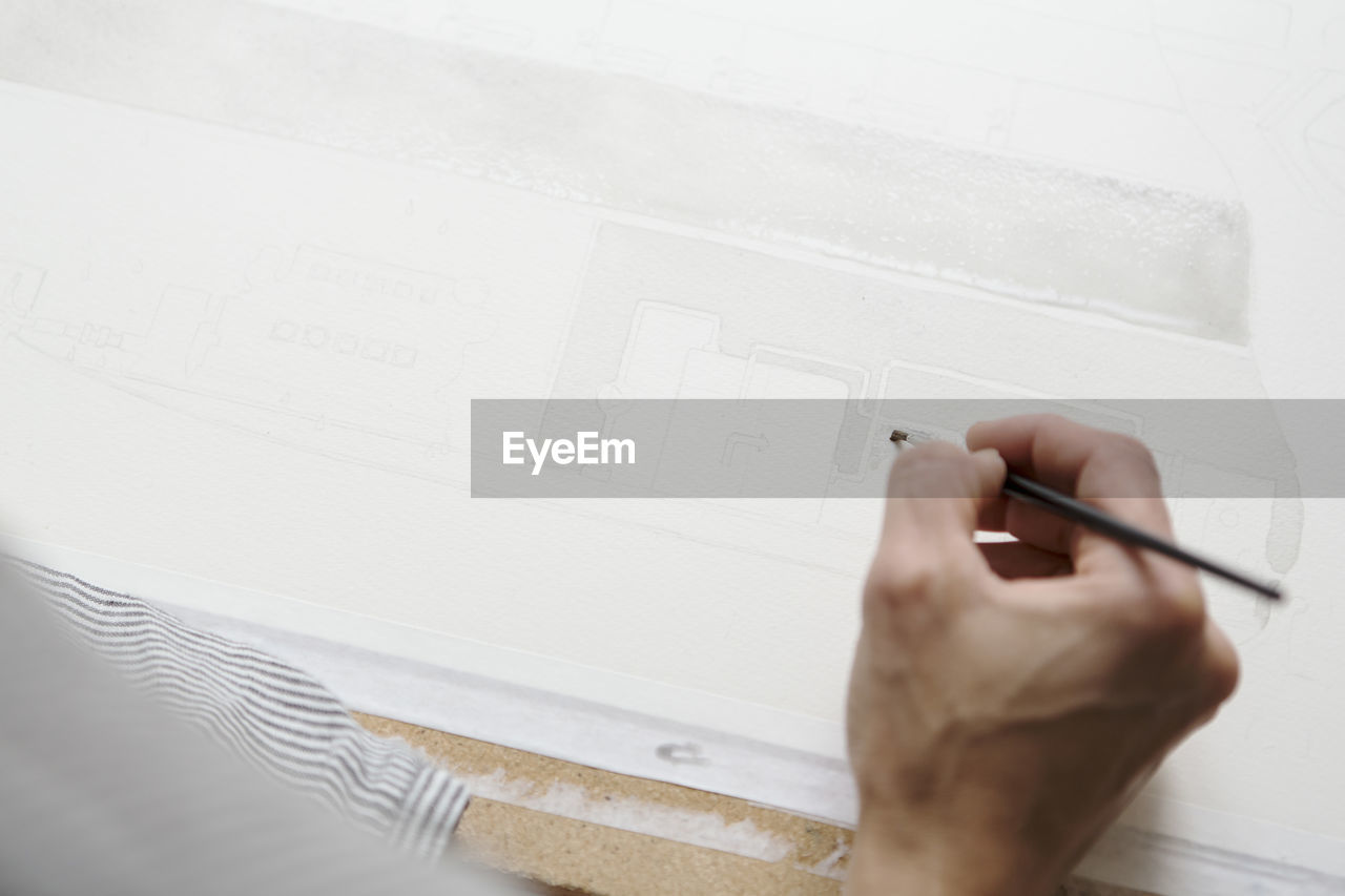 Cropped image of artist's hand painting on canvas at table