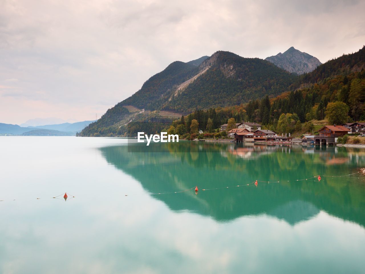 Village on the bank of alps lake. high mountain peaks in mirror of gren water level. 