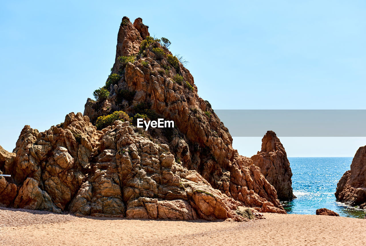 Rock formations on shore at beach in tossa de mar