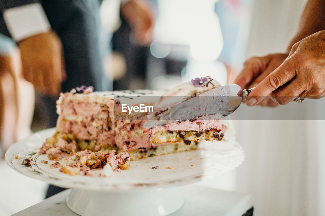 Cropped hands serving cake in plate at wedding ceremony