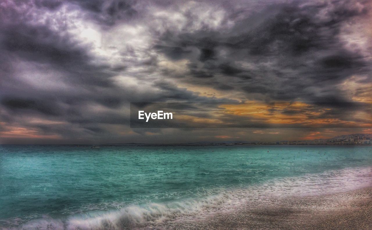 SCENIC VIEW OF BEACH AGAINST DRAMATIC SKY