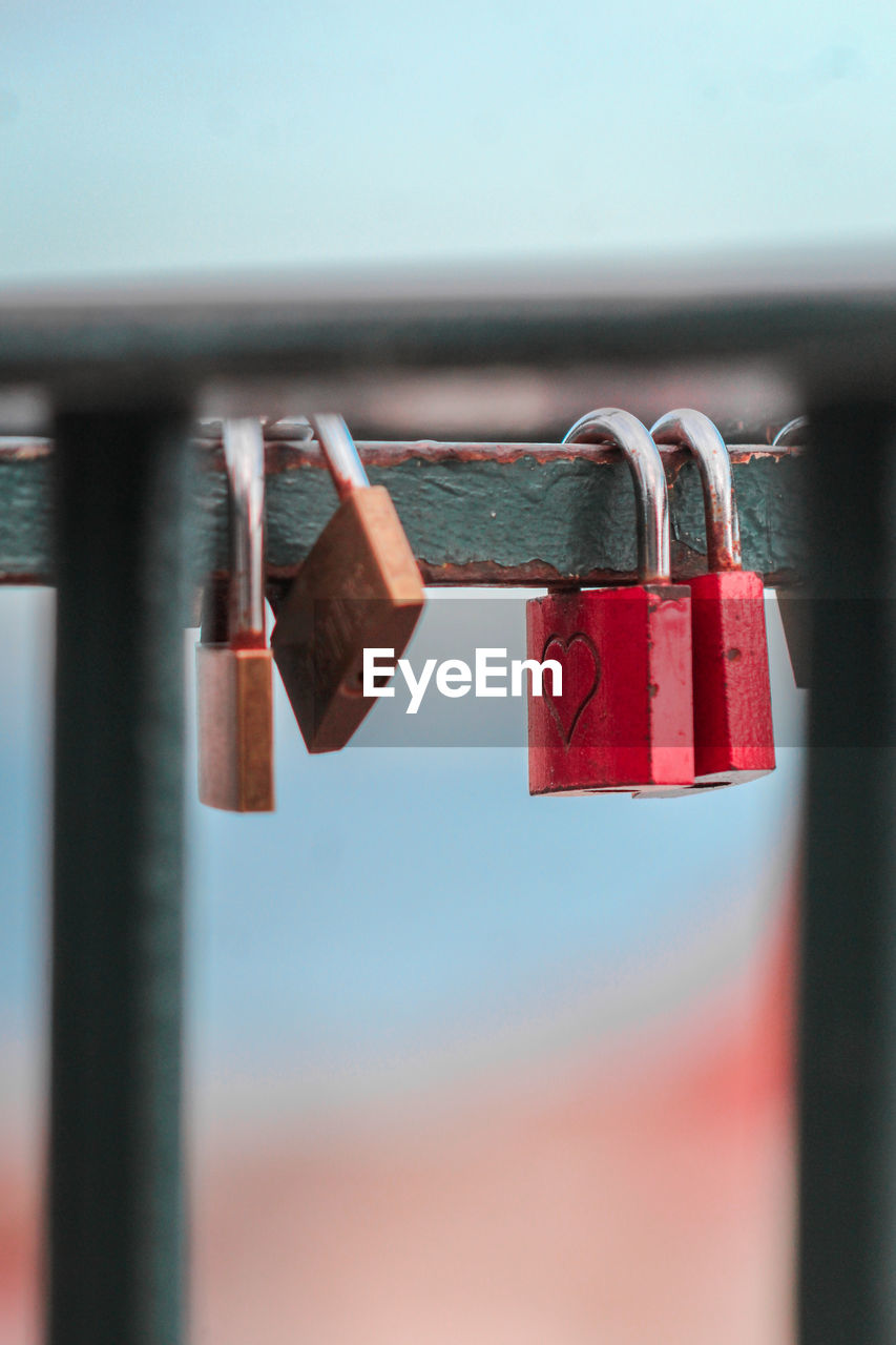 Close-up of padlocks hanging on railing against sky