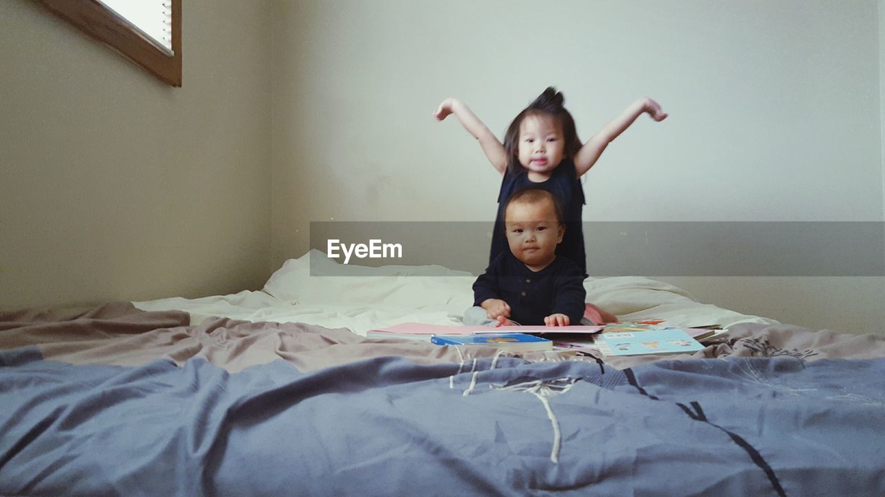 Portrait of siblings on bed at home
