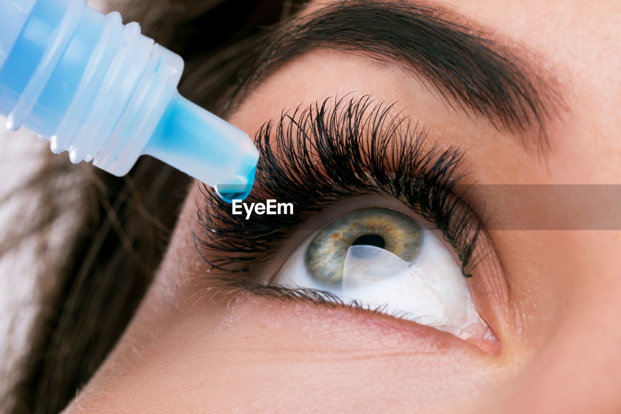 Close-up of woman putting drip in eye