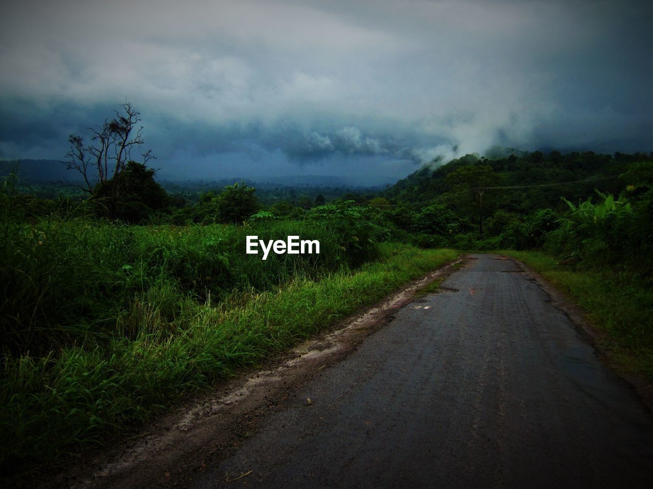 Empty road on field against cloudy sky