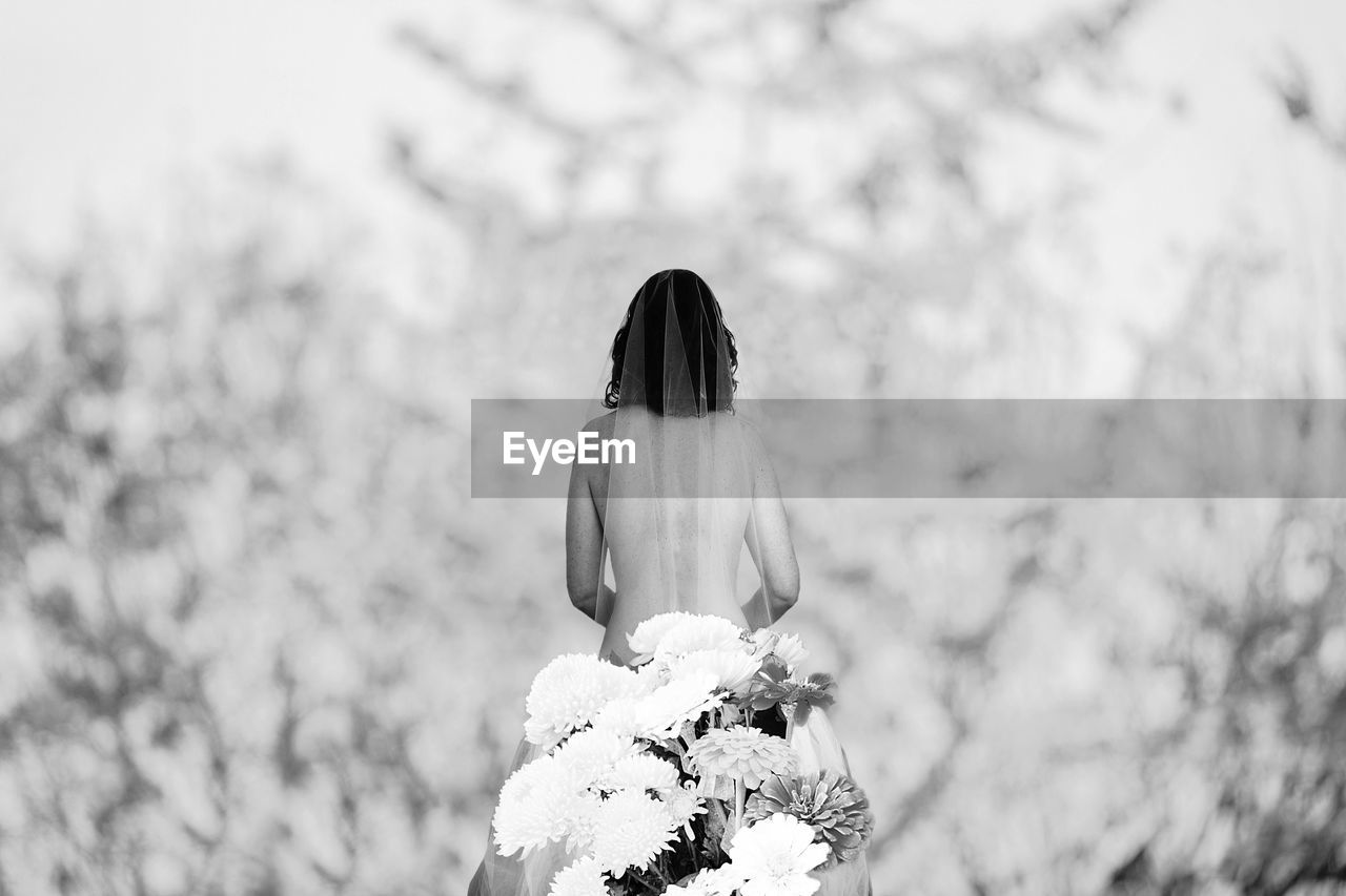 REAR VIEW OF WOMAN WITH UMBRELLA ON FLOWER