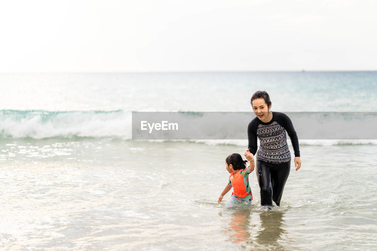 FULL LENGTH OF FATHER AND DAUGHTER ON BEACH