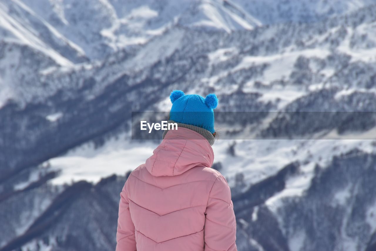 Rear view of woman standing against snowcapped mountain