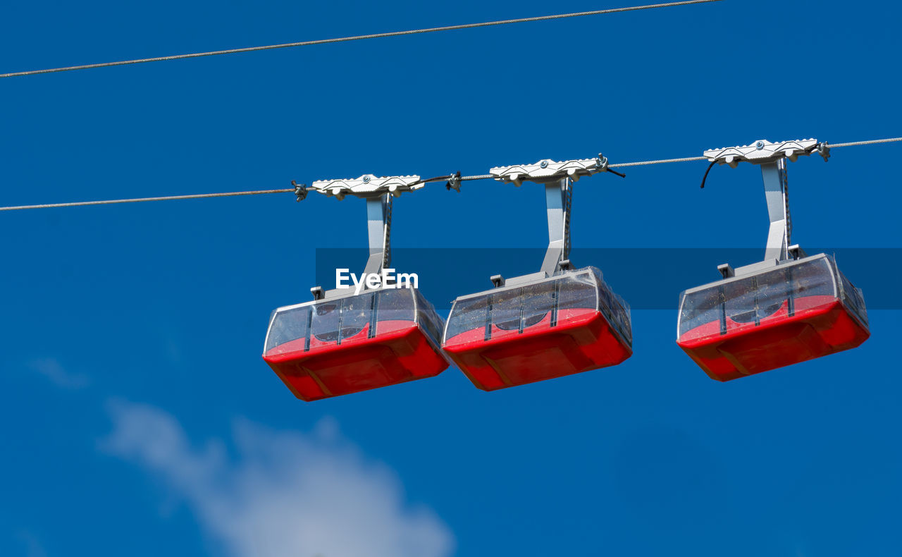 Low angle view of overhead cable cars against sky