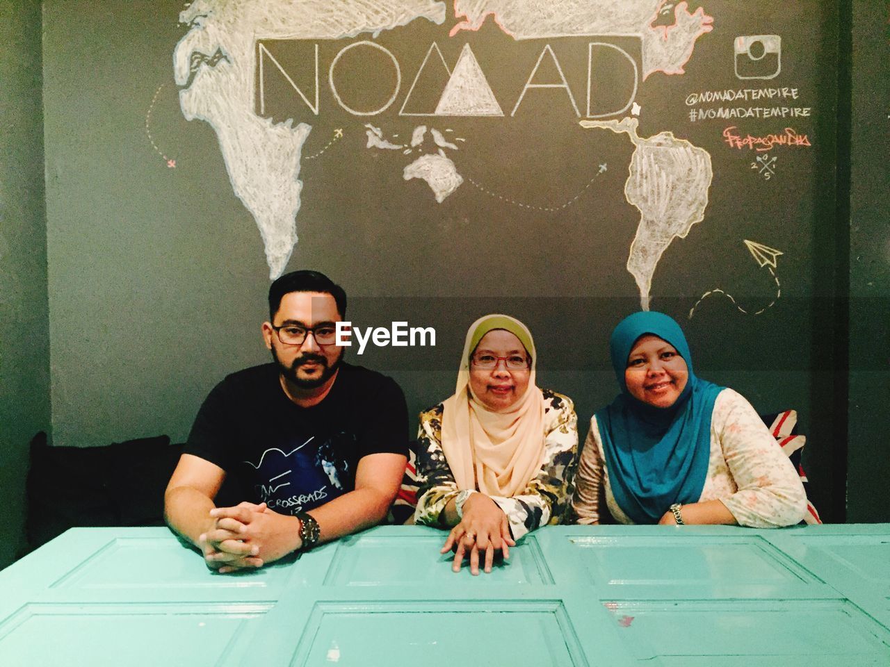 Portrait of people sitting at table against wall