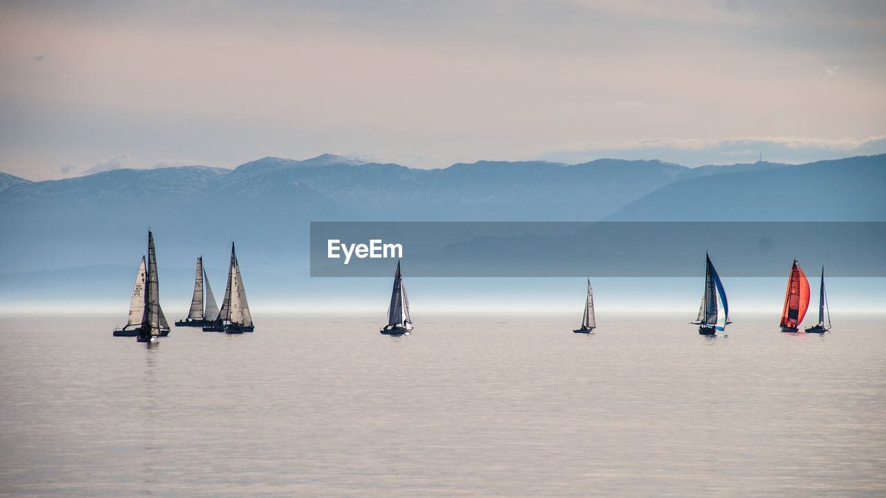 SAILBOAT SAILING IN SEA AGAINST SKY