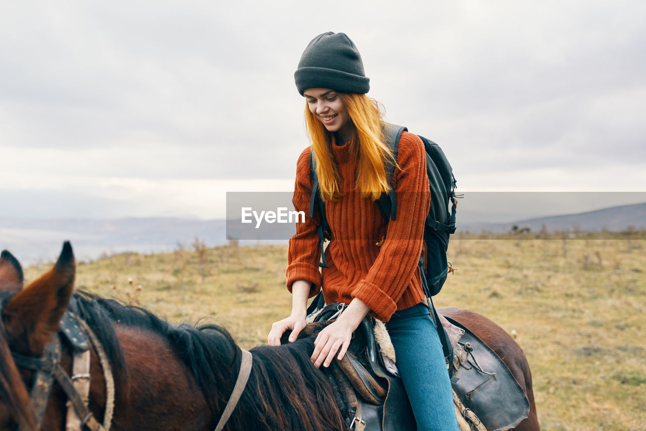 FULL LENGTH OF YOUNG WOMAN RIDING HORSE