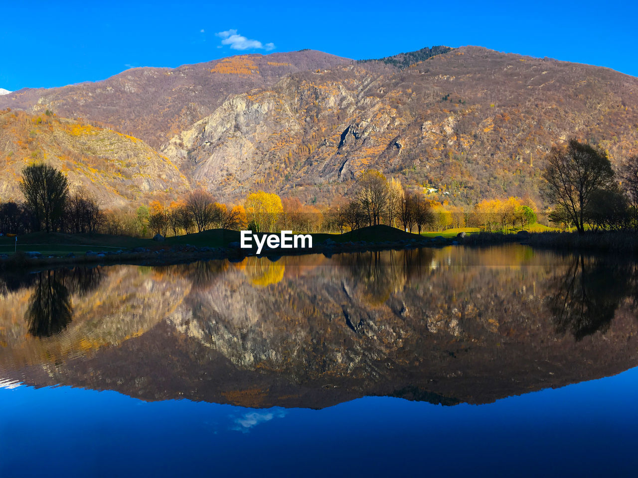 Scenic view of lake by mountains against clear blue sky
