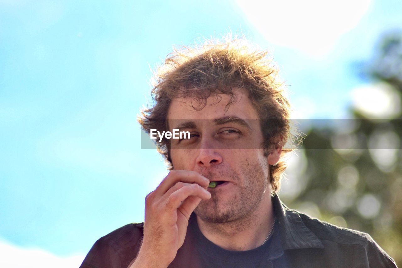 Man with messy hair looking away against sky