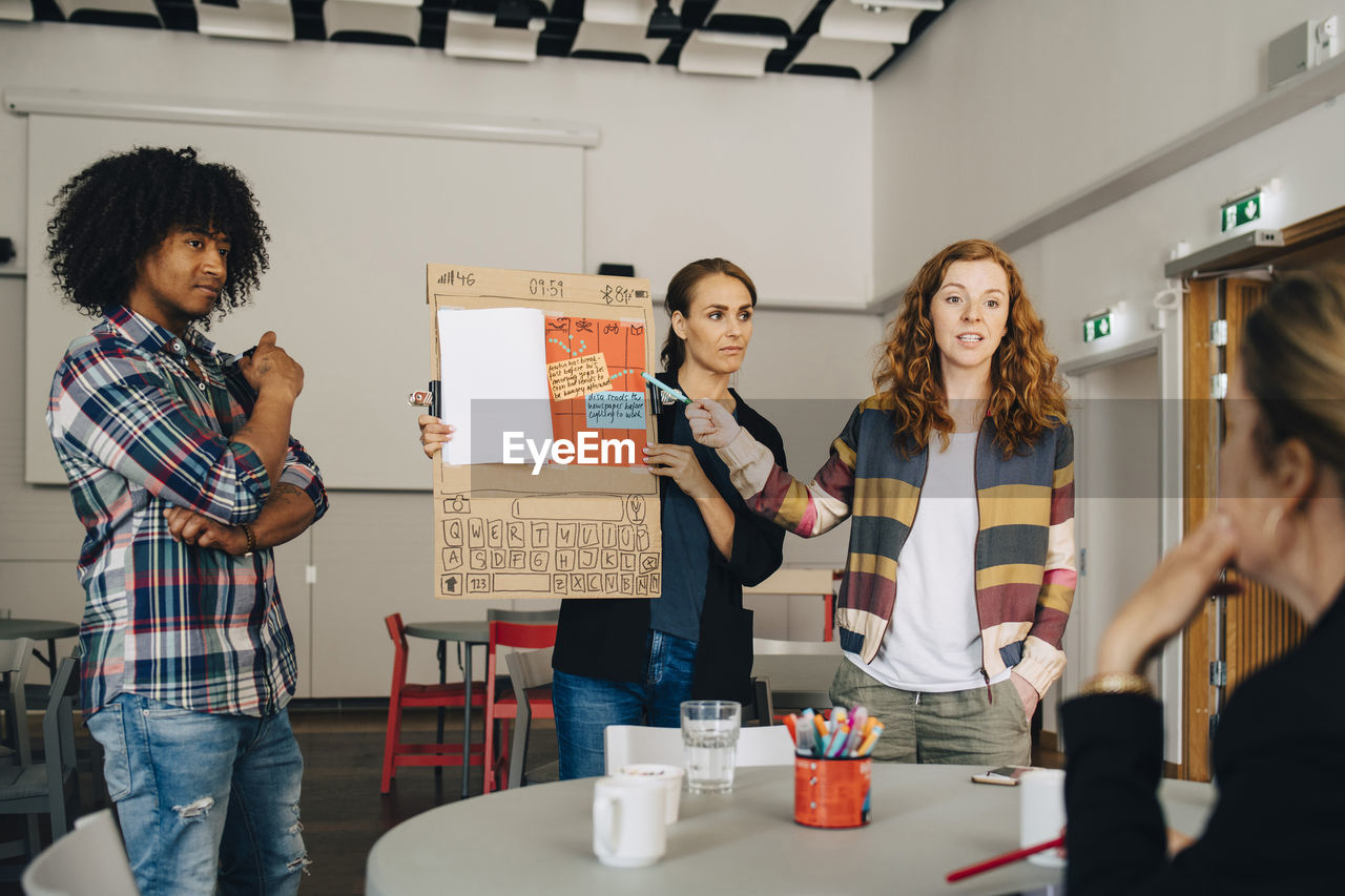 Confident businesswoman with colleagues explaining strategy to female manager at creative office