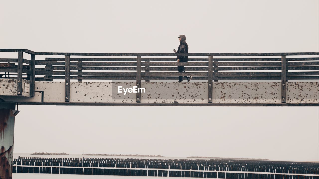 Low angle view of man standing on bridge against sky