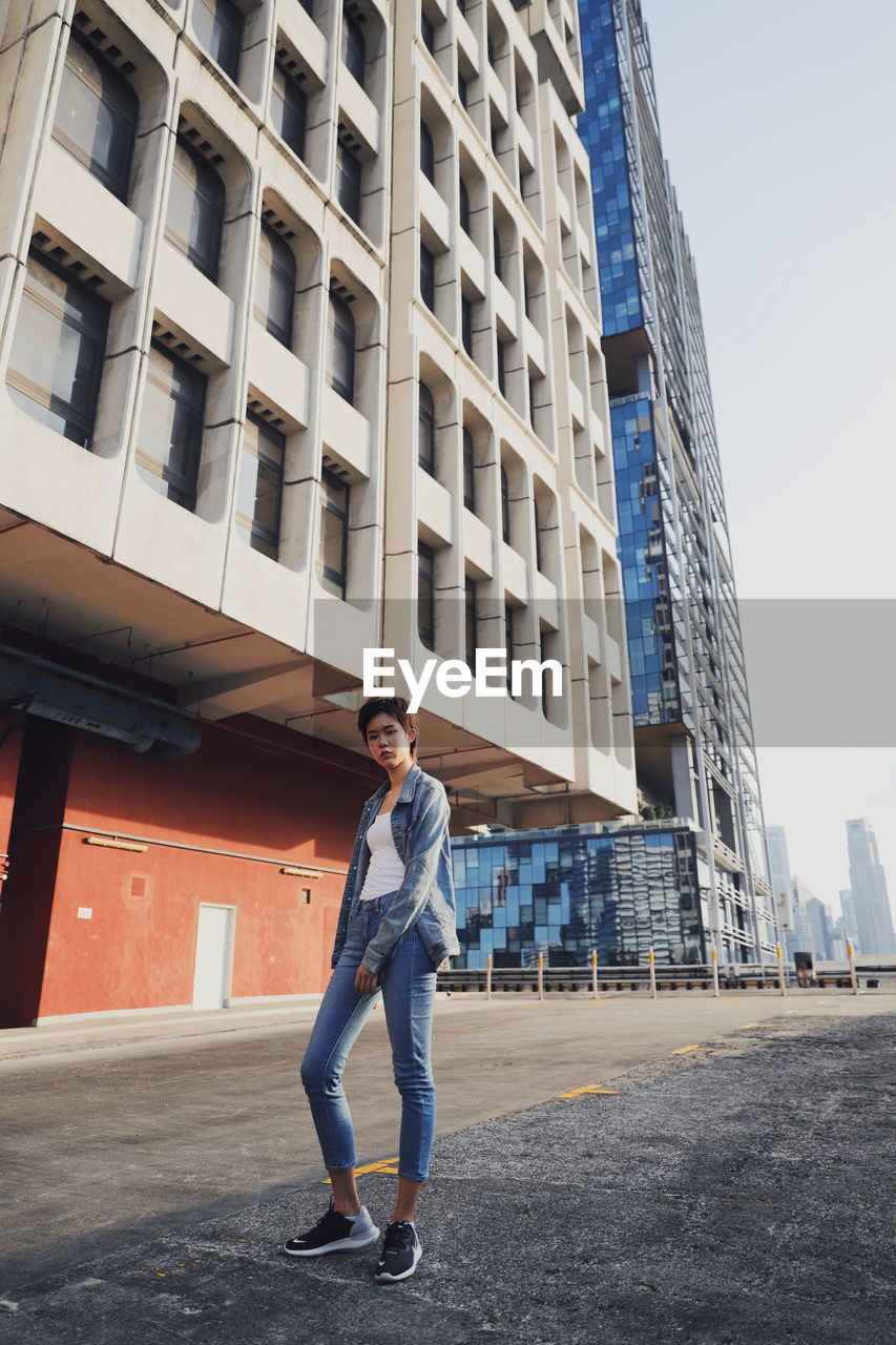 Full length of woman standing against buildings in city