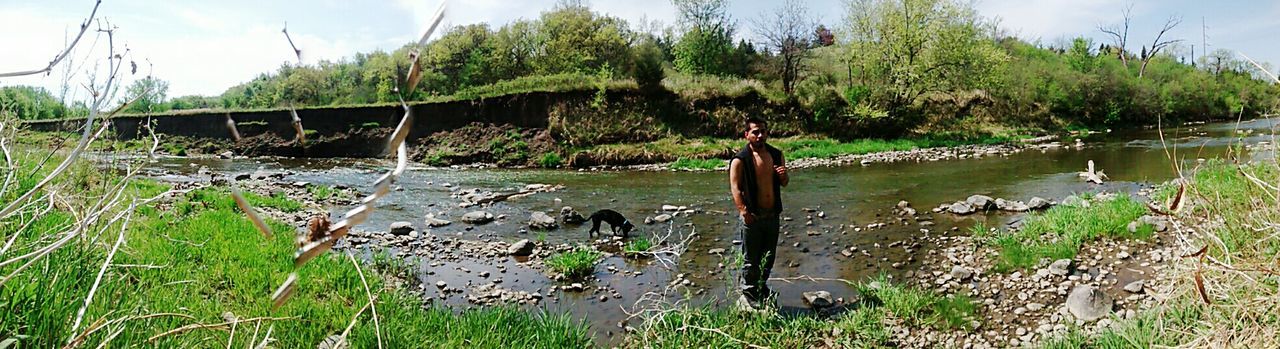 Panoramic view of man standing on rock at stream