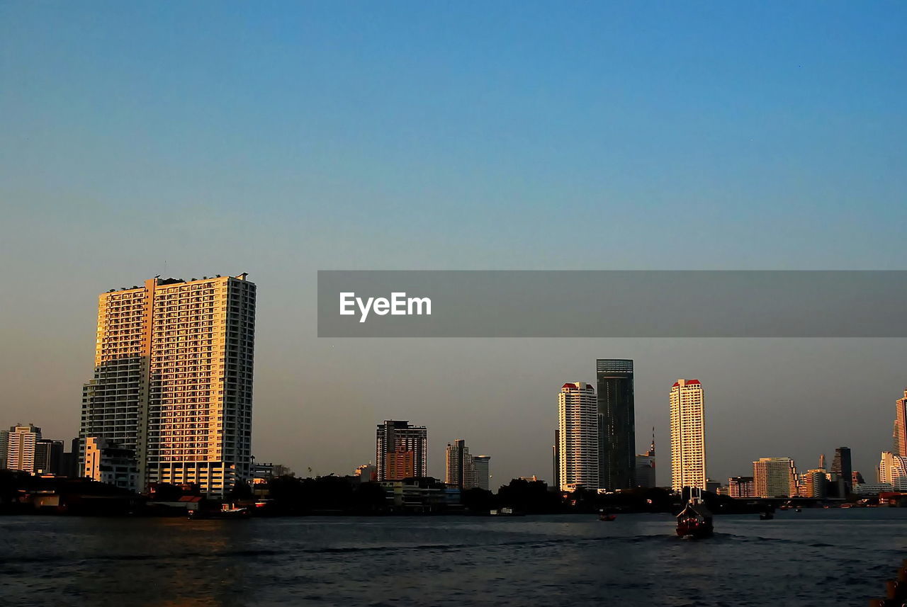 RIVER BY BUILDINGS AGAINST CLEAR SKY