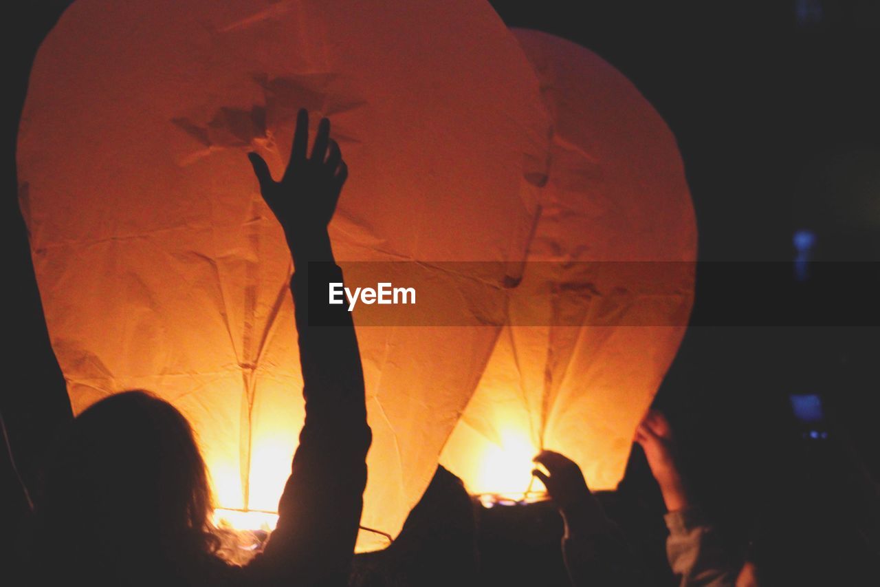 People flying paper lanterns at night
