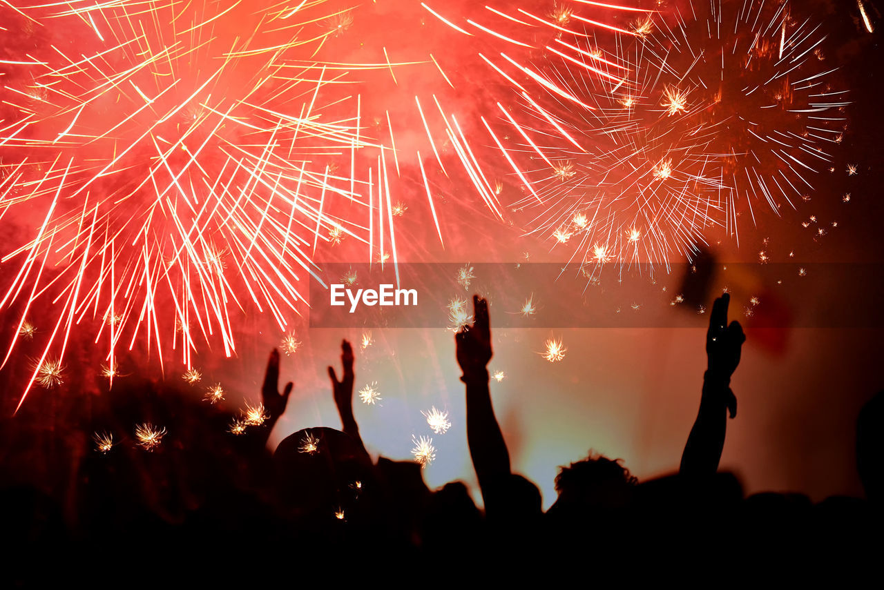 Silhouette people enjoying firework display at night