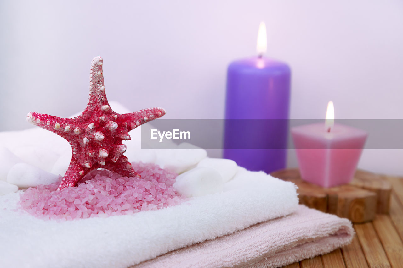 Close-up of burning candles and starfish on towels