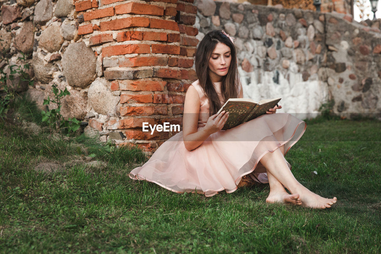 Young woman sitting on brick wall