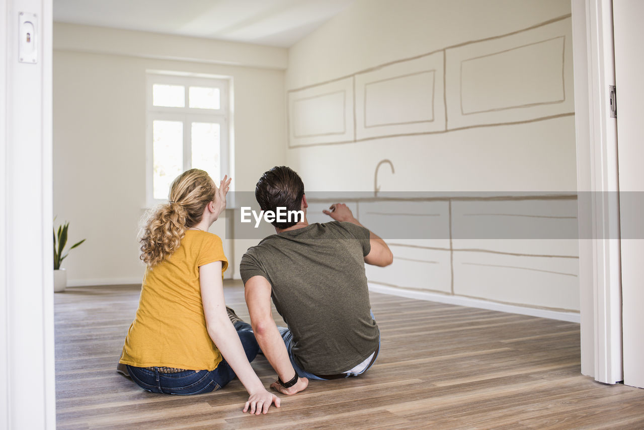 Young couple in new home sitting on floor thinking about interior design