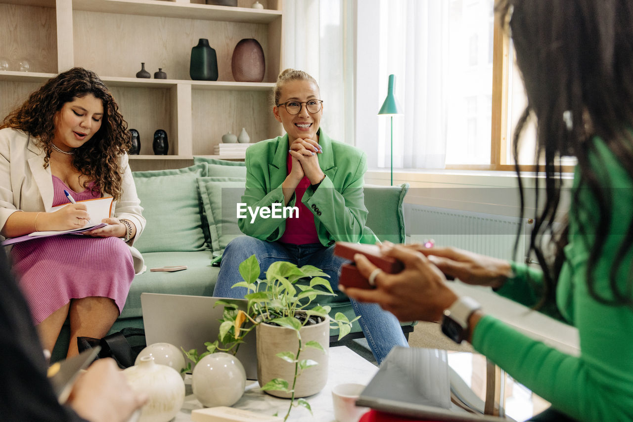 Smiling female boss listening to female colleague during meeting at office