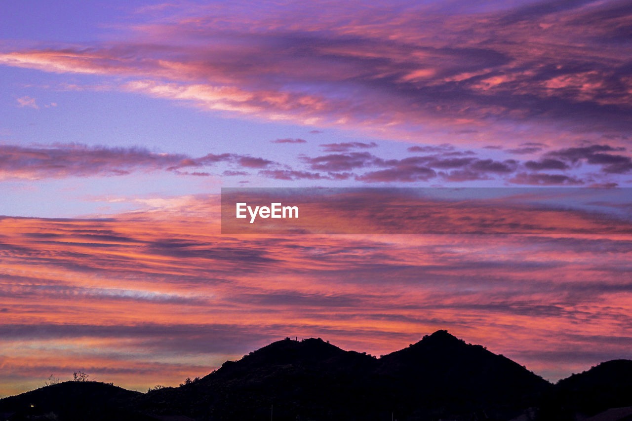 SCENIC VIEW OF SILHOUETTE MOUNTAINS AGAINST DRAMATIC SKY