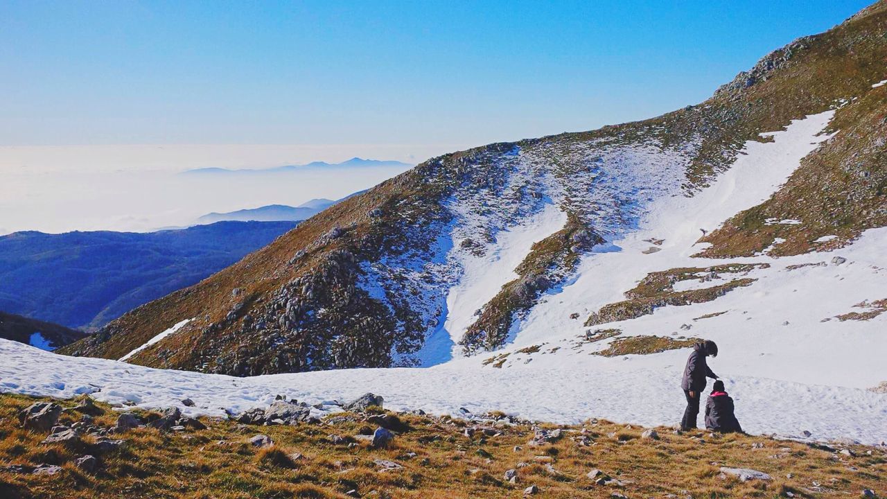 People on mountain against sky during winter