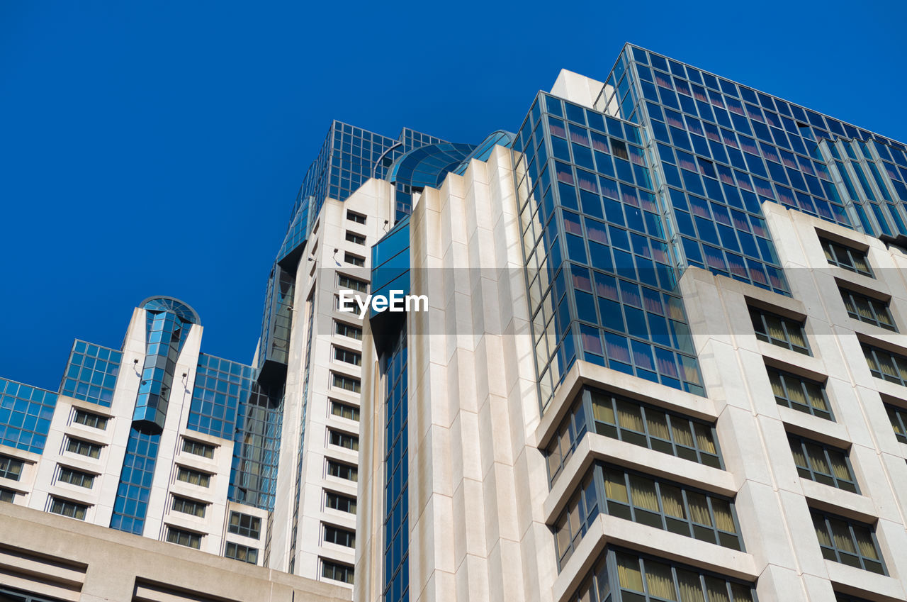 Low angle view of modern buildings against blue sky