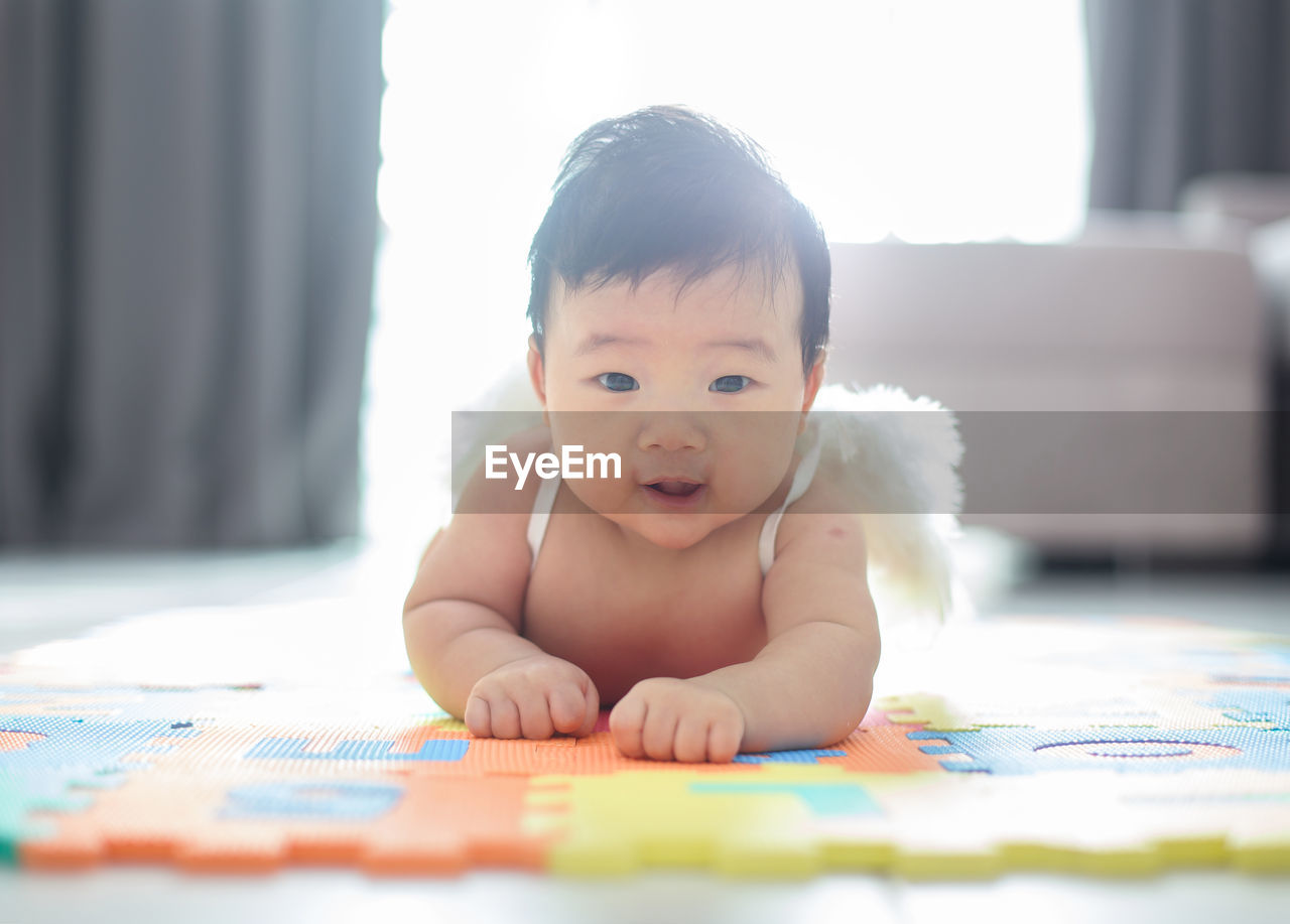 Portrait of cute baby boy wearing costume wing while lying at home