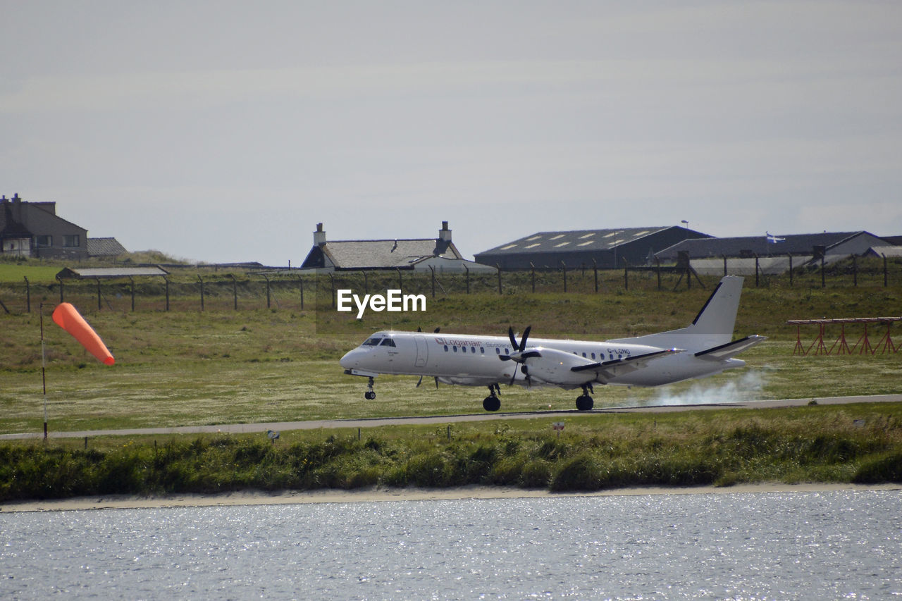 AIRPLANE FLYING OVER RUNWAY