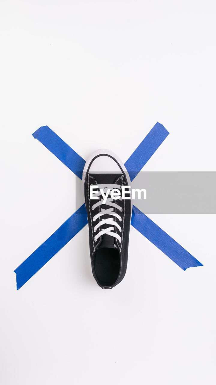 Directly above shot of canvas shoe and adhesive tape on white background