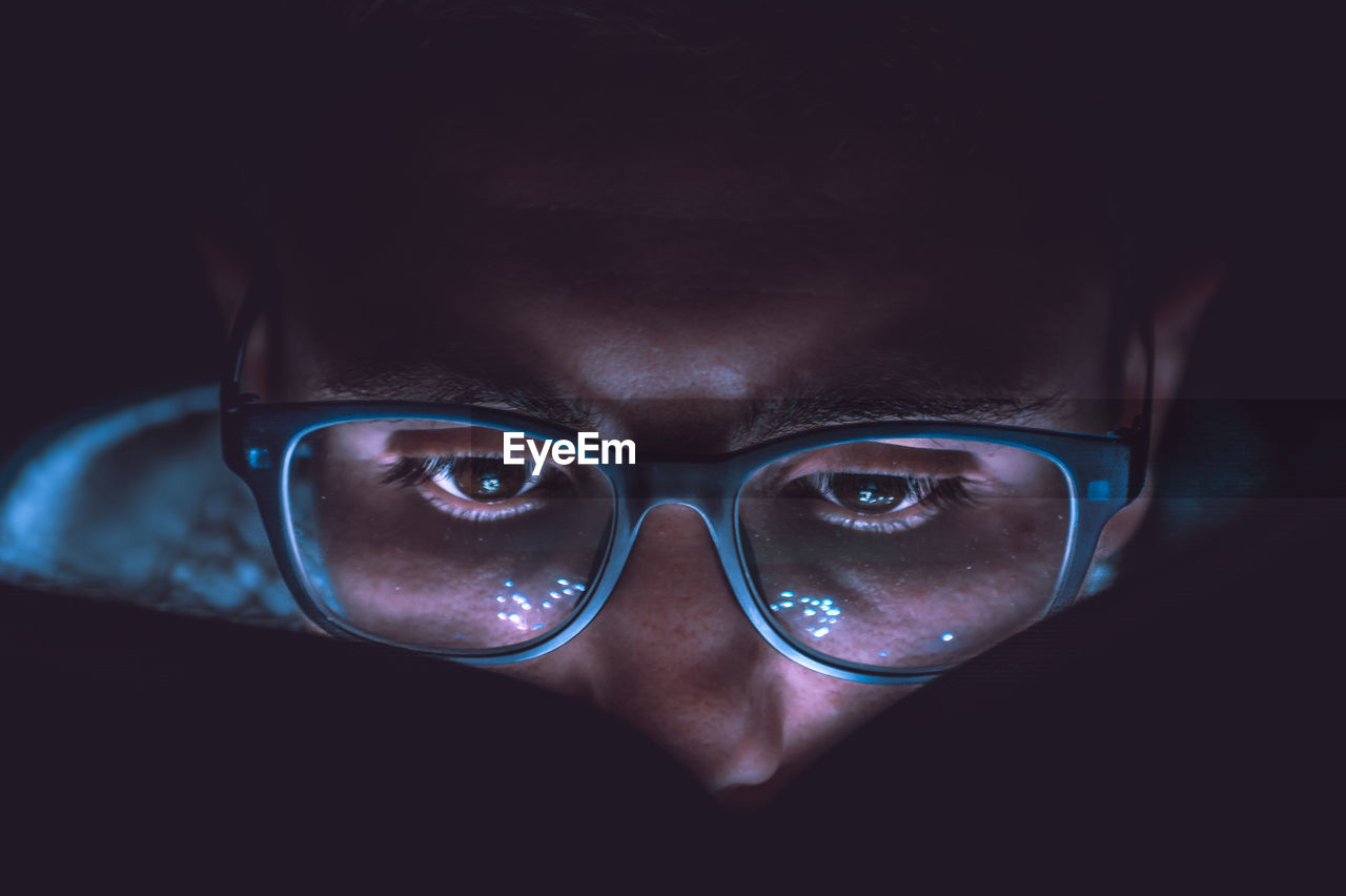 Close-up of man wearing eyeglasses in darkroom