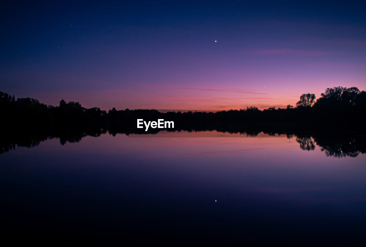 Scenic view of lake against sky at sunset