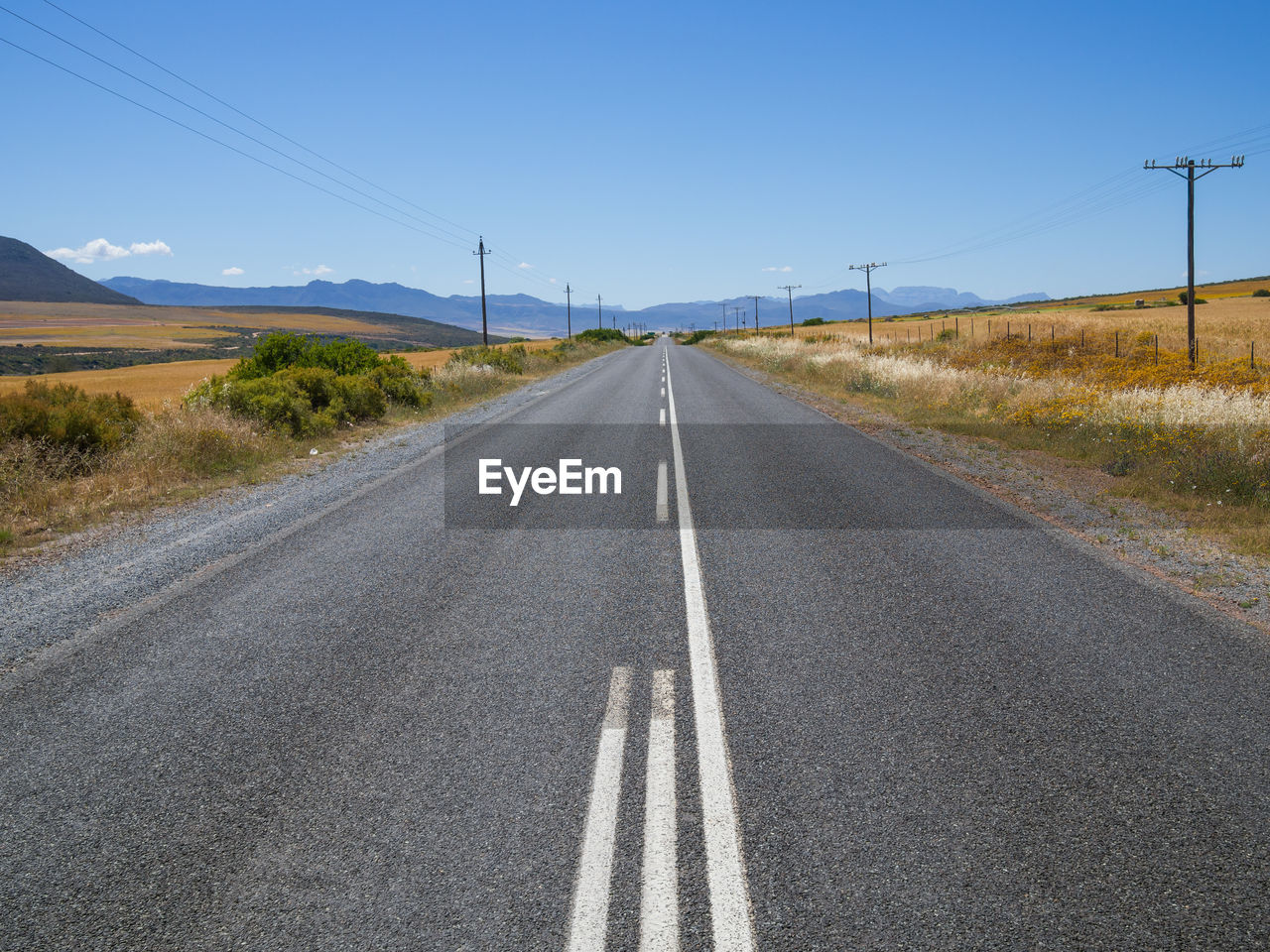 Empty road on landscape against clear sky with cederberg mountains in background, south africa