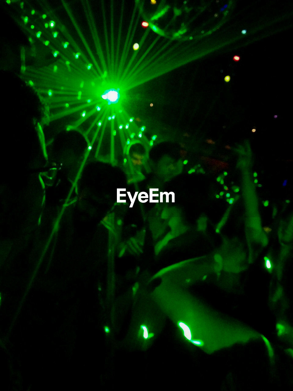 People enjoying at nightclub against green laser lights